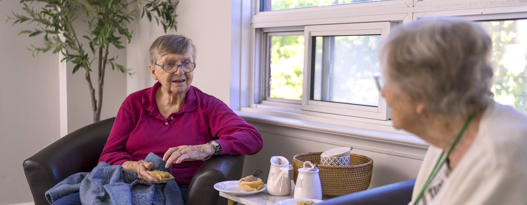 Two residents in a suite enjoying a visit and tea